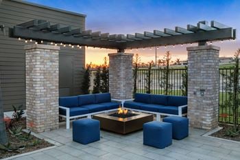 A patio with blue couches and a fire pit